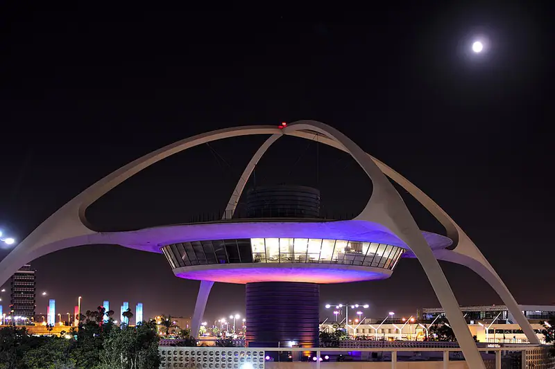 Space-age white arched tower with a lit restaurant at night