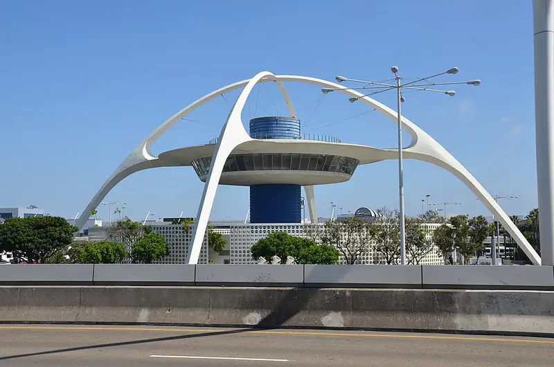 White saucer-shaped restaurant on two huge arched legs, under a blue sky