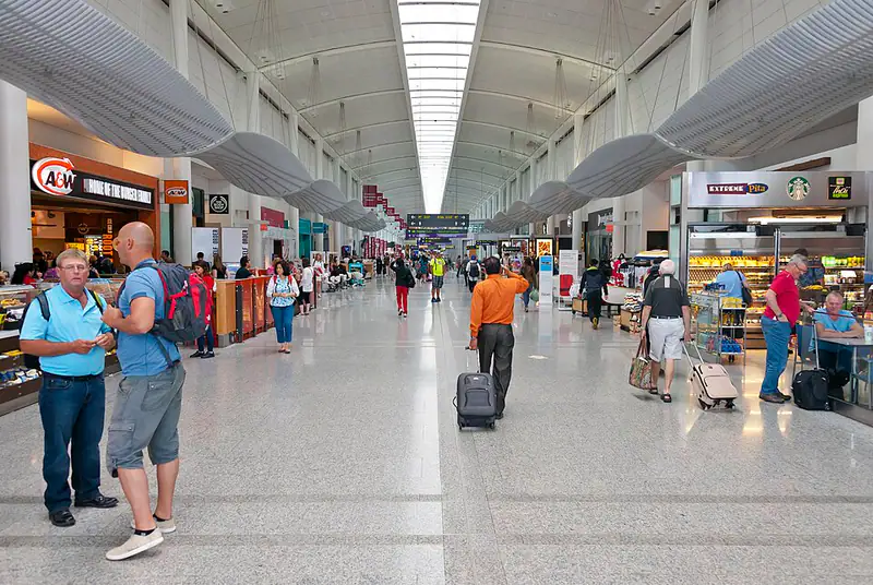 Wide shop-lined concourse with travellers under a long skylight