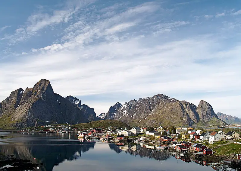 Fishing village at the foot of jagged peaks across still water
