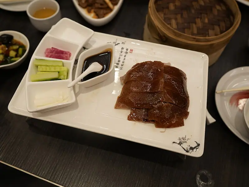 Slices of roast duck with sauces and cucumber on a tray
