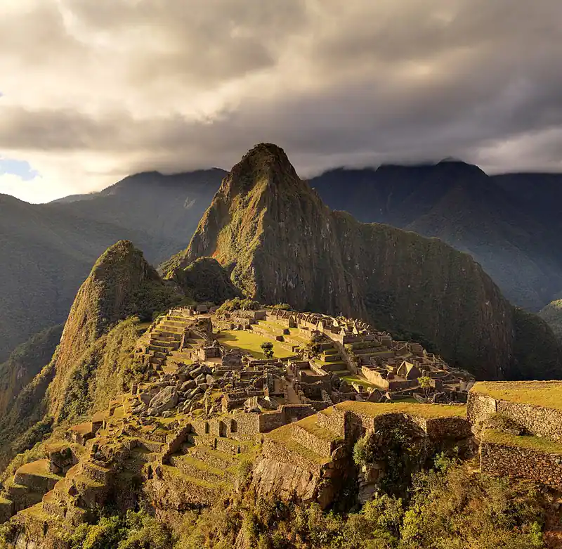 Inca citadel ruins on a mountain ridge under clouds