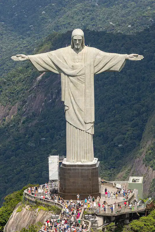 Giant statue with outstretched arms on a mountain peak