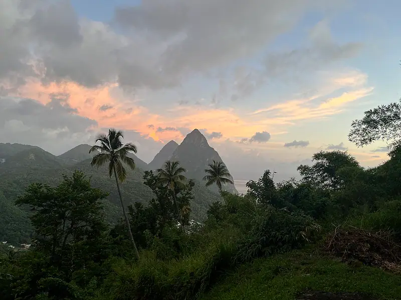 Twin pointed volcanic peaks above palm trees at dusk
