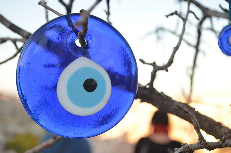 Blue glass evil eye charm hanging on a bare branch