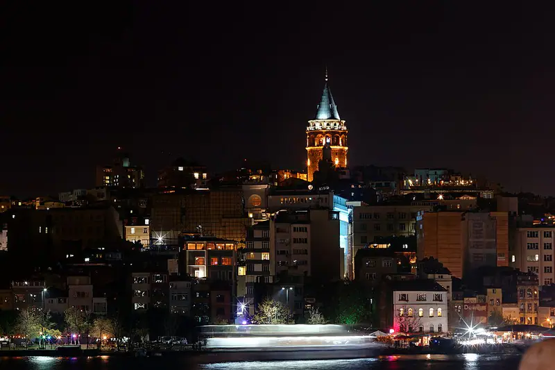 Galata Tower lit up at night above the city roofs